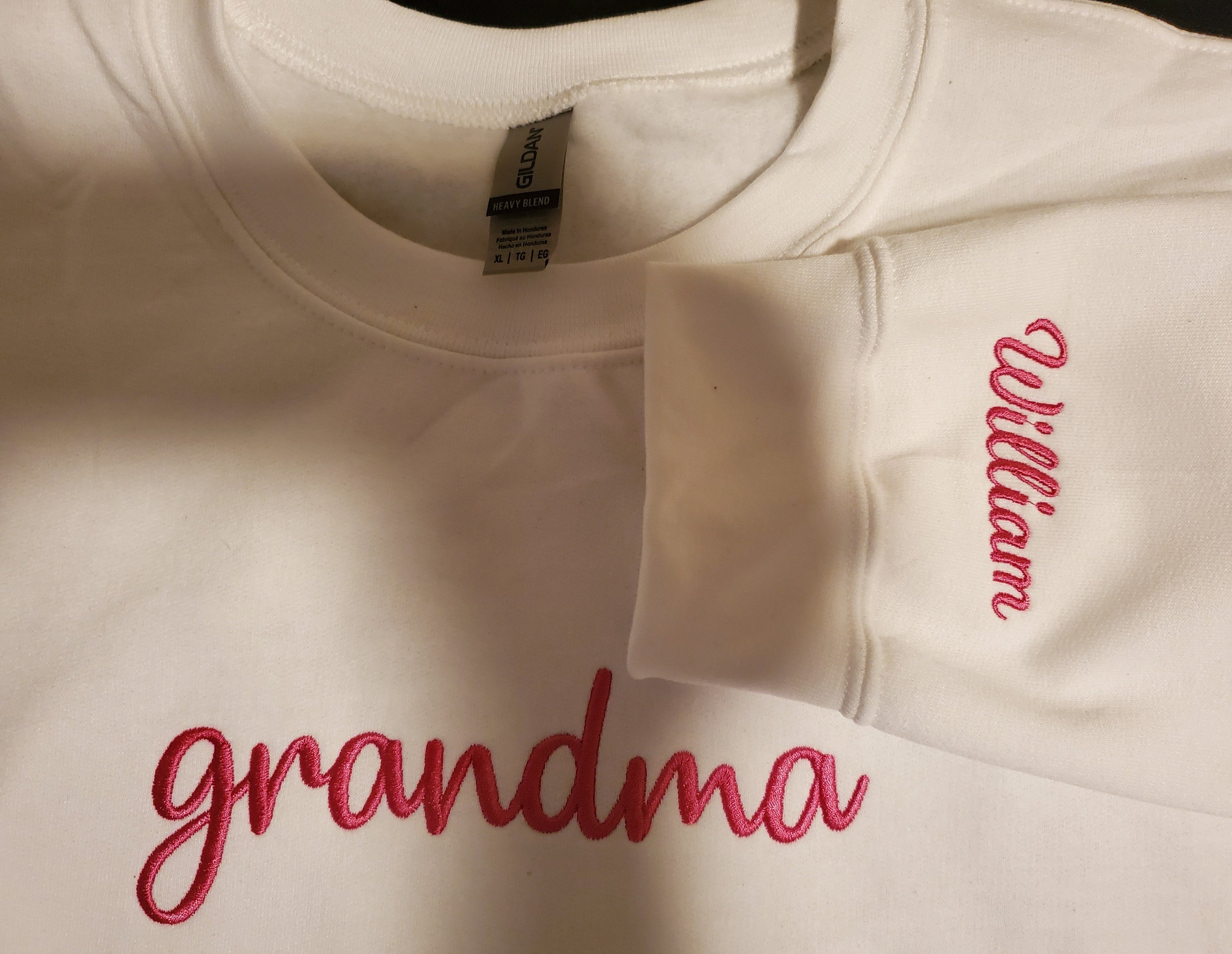 White sweatshirt with 'grandma' and 'William' embroidered in red on a plain background