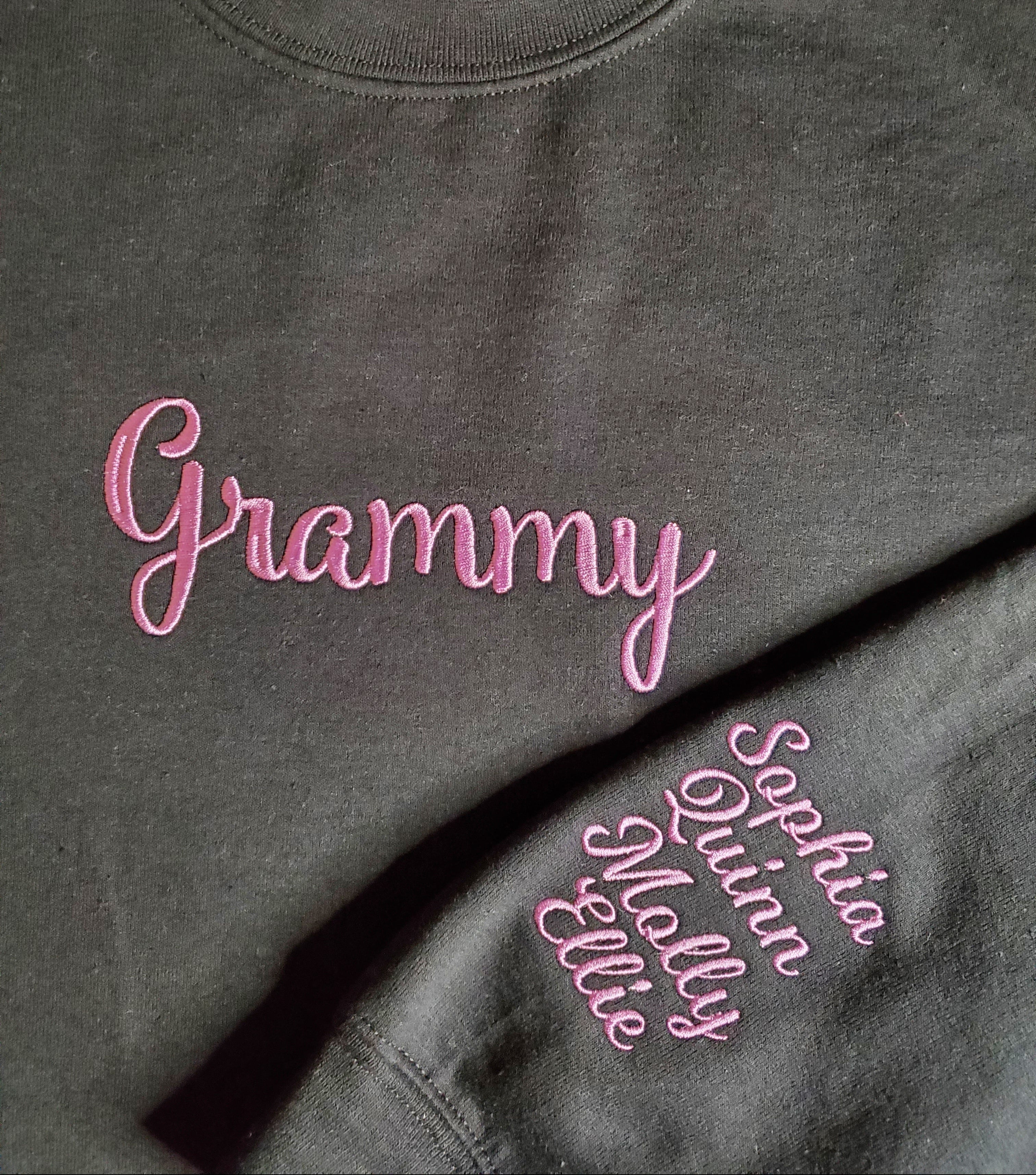 Gray sweatshirt with pink embroidered names on a plain background