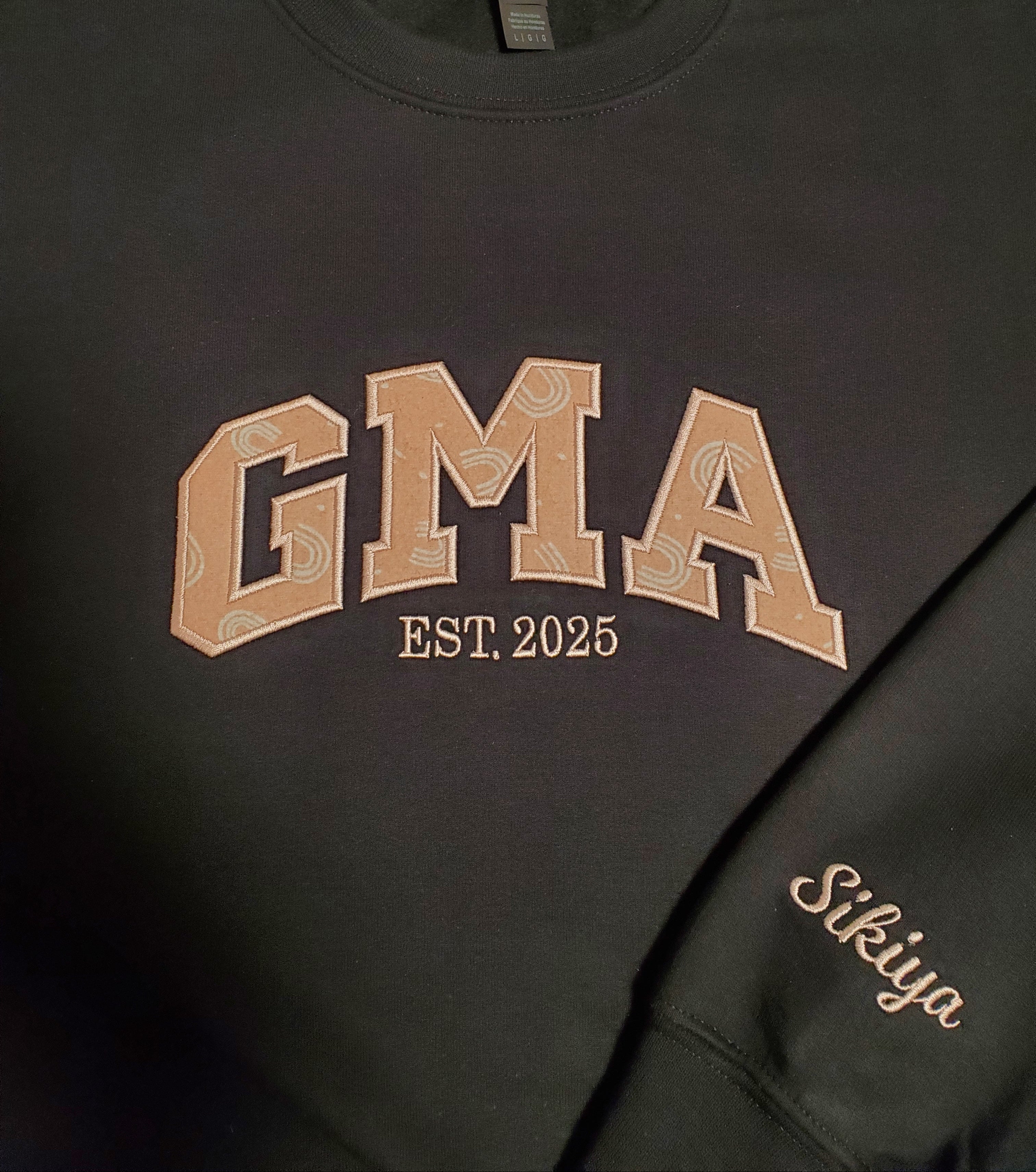 Black sleeveless shirt with 'GMA' and 'Sikiya' text on a plain background